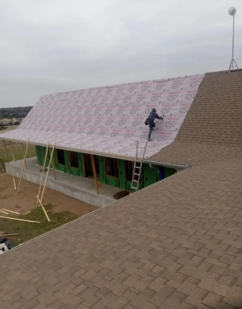 Worker preparing underlayment for a metal roof installation in Montgomery